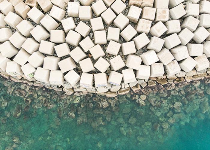 Aerial view of armoured breakwater in green sea waves