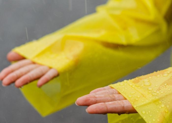 Close up of someone's hands under rain in yellow raincoat